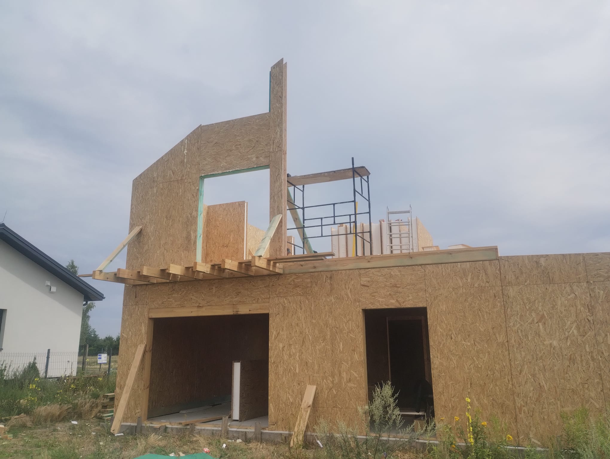 Widok na konstrukcję stropu gęstożebrowego przygotowanego do zalania betonem. Widać ułożone pustaki stropowe, zbrojenie z prętów stalowych oraz rury instalacyjne wystające z konstrukcji.